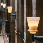 Interior hallway with lit sconces on brick walls, blurred people in background.