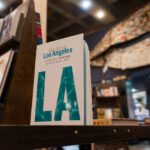 "Writing Los Angeles: A Literary Anthology" book cover on a wooden shelf in a bookstore with other books around it.